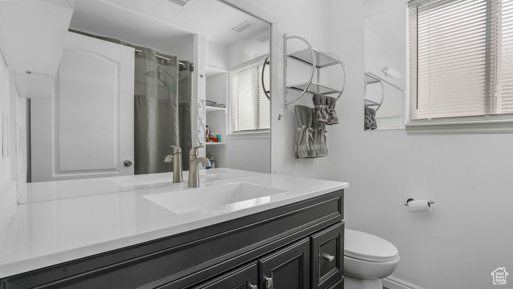Full bathroom featuring toilet, a shower with curtain, and a wealth of natural light