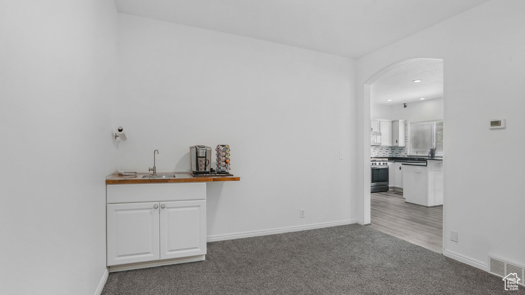 Interior space featuring a sink, arched walkways, carpet, gas range, and visible vents