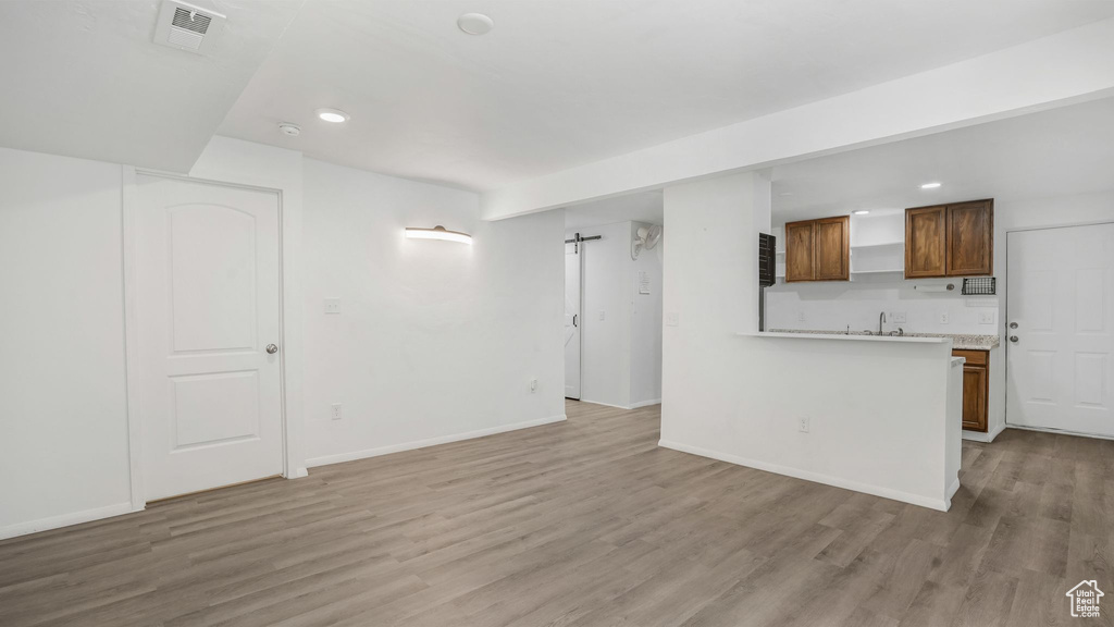 Unfurnished living room with visible vents, baseboards, light wood-type flooring, recessed lighting, and a sink