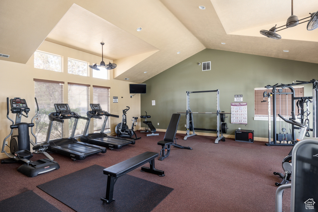 Exercise room featuring high vaulted ceiling, visible vents, and baseboards