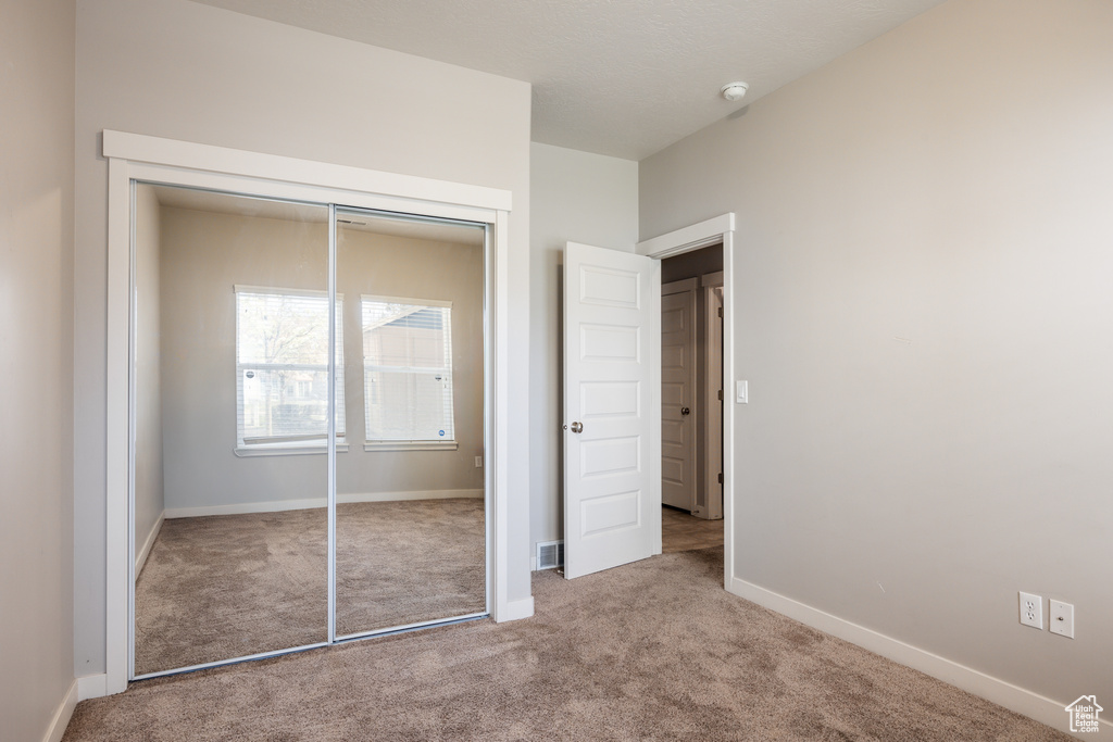 Unfurnished bedroom with a closet, carpet flooring, baseboards, and visible vents