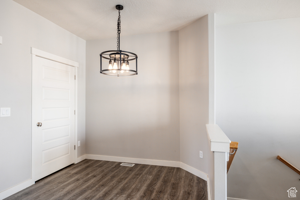 Spare room featuring baseboards, visible vents, dark wood-style floors, and a chandelier