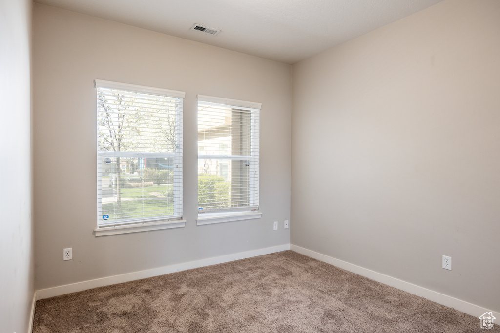 Carpeted empty room with baseboards and visible vents