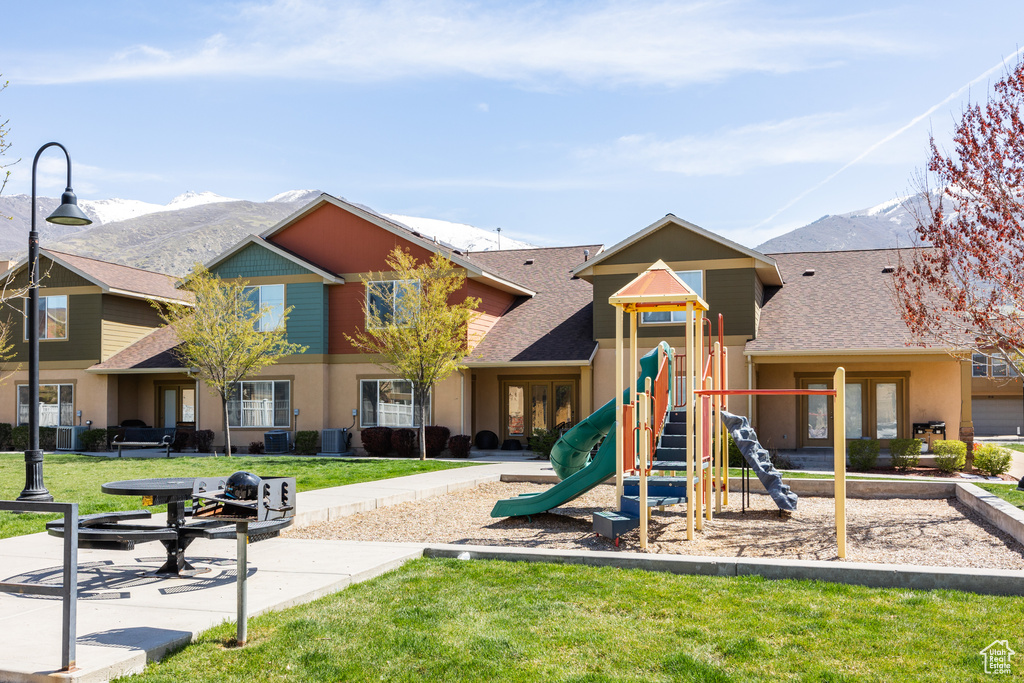 Community play area featuring a mountain view, a yard, and central AC unit