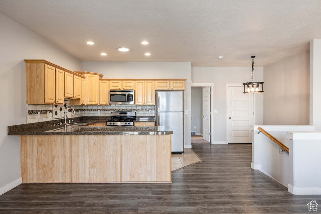 Kitchen featuring light brown cabinetry, stainless steel appliances, recessed lighting, a peninsula, and decorative backsplash