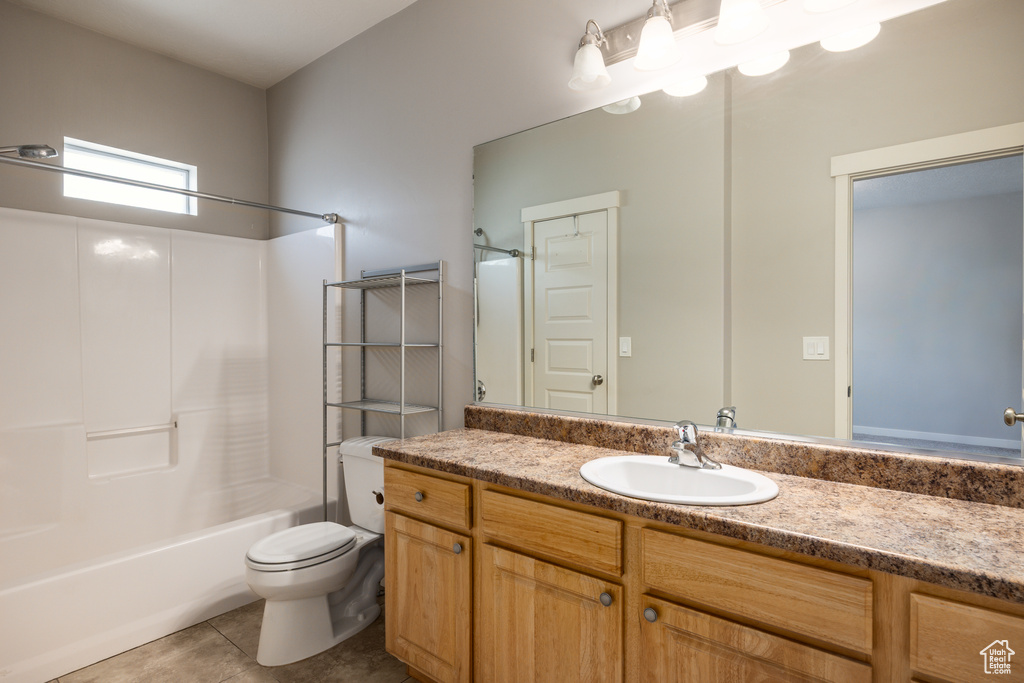 Bathroom featuring vanity, tile patterned flooring, toilet, and tub / shower combination