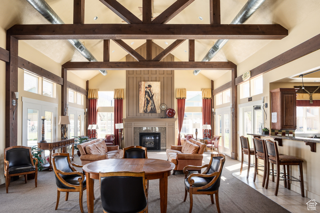 Dining room with high vaulted ceiling, light colored carpet, beam ceiling, and a fireplace