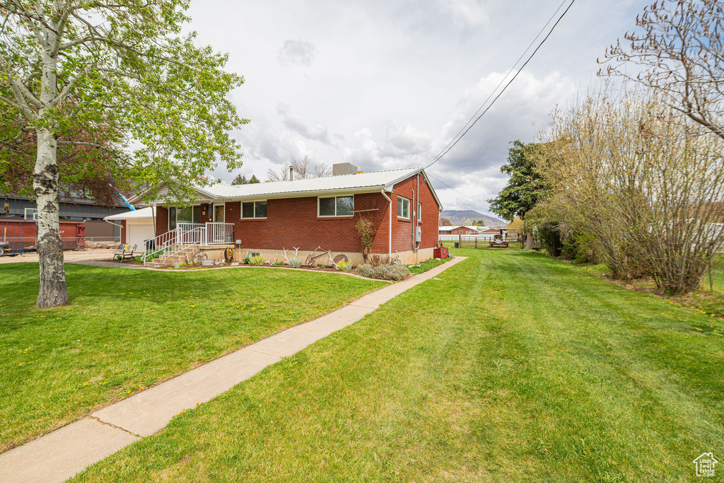 Ranch-style home featuring metal roof, an attached garage, brick siding, and a front yard