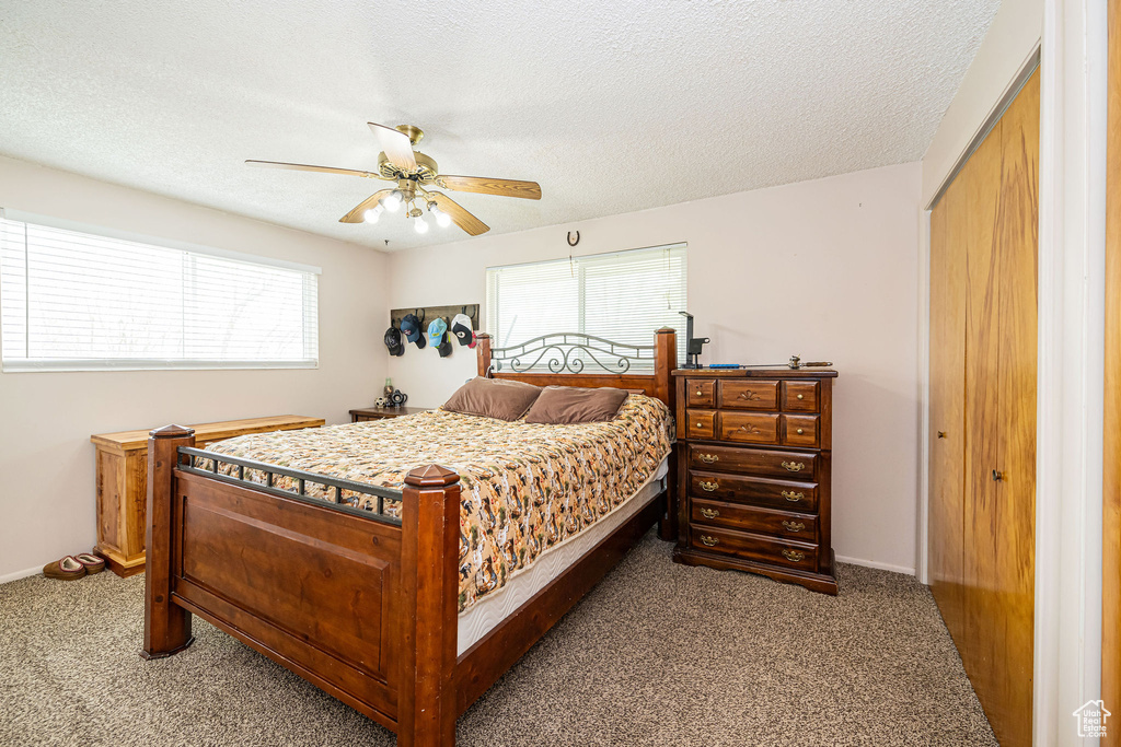 Bedroom with a textured ceiling, ceiling fan, baseboards, and carpet