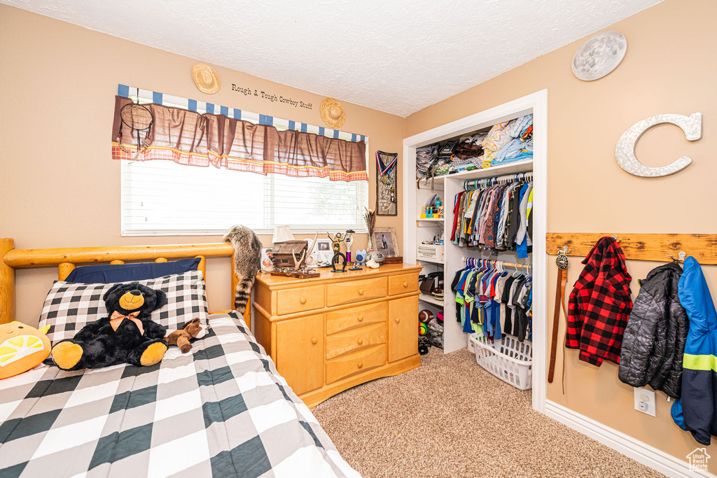 Bedroom with carpet flooring, a textured ceiling, and a closet