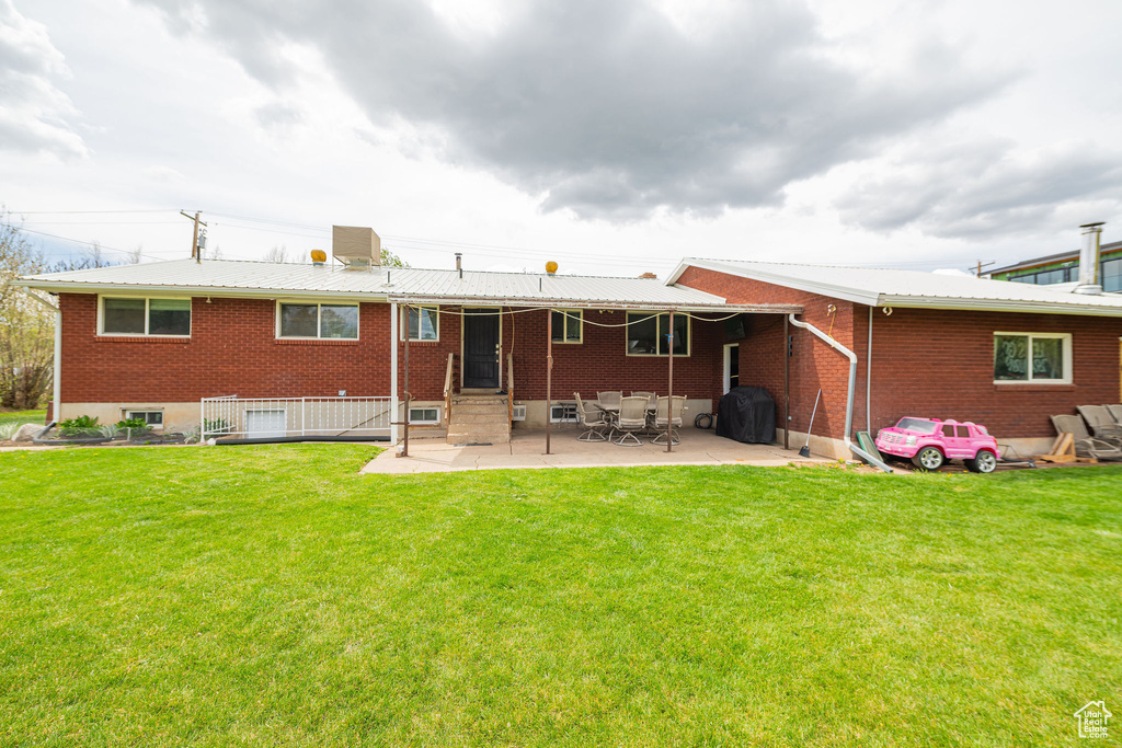 Back of house with a lawn, a patio, brick siding, and entry steps