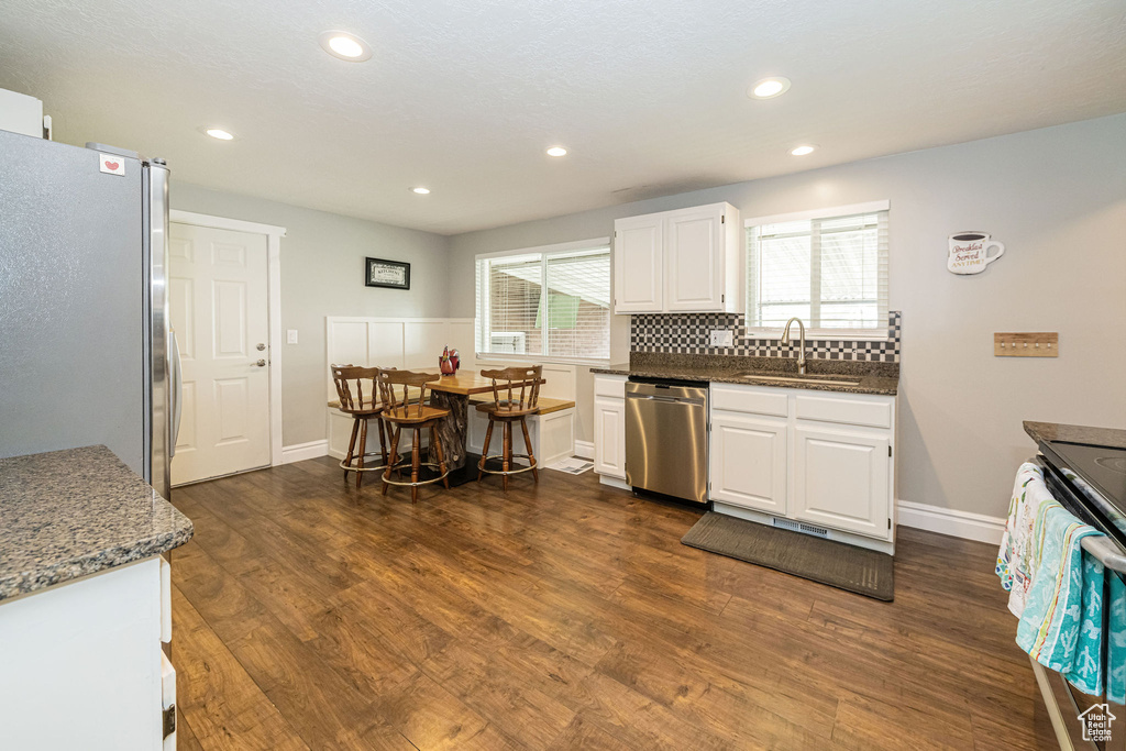 Kitchen featuring a sink, white cabinetry, appliances with stainless steel finishes, and dark wood-style floors