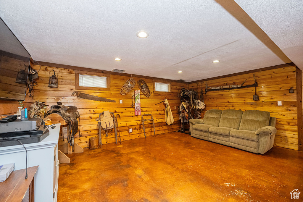 Basement with recessed lighting, wood walls, a textured ceiling, and visible vents