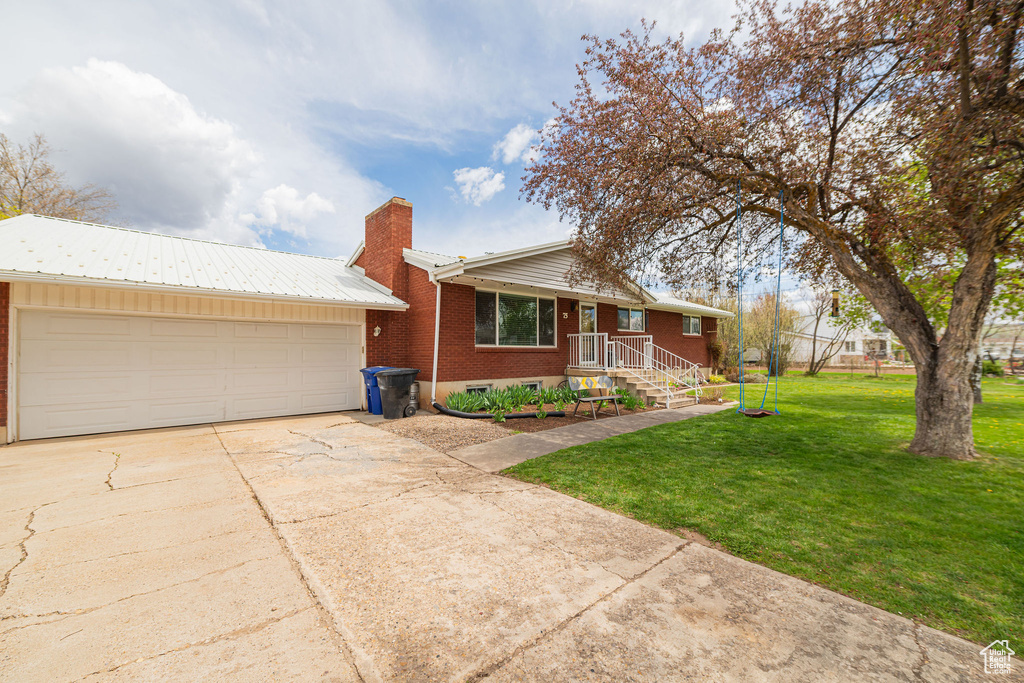 View of front facade featuring a front yard, a chimney, brick siding, concrete driveway, and an attached garage