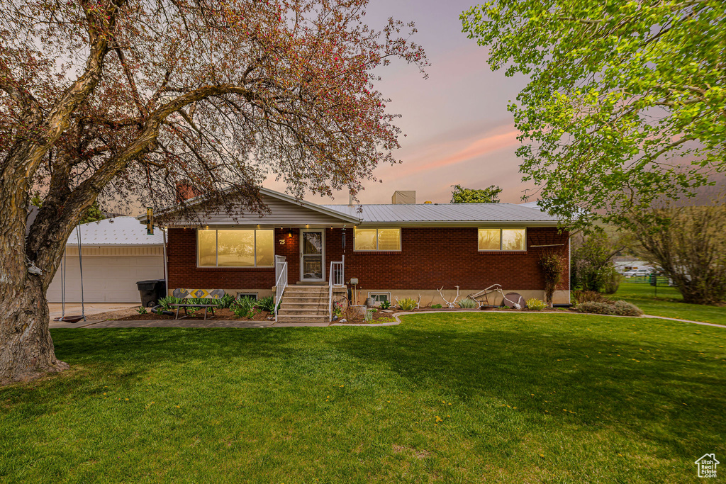 Ranch-style house with a yard, brick siding, and a chimney