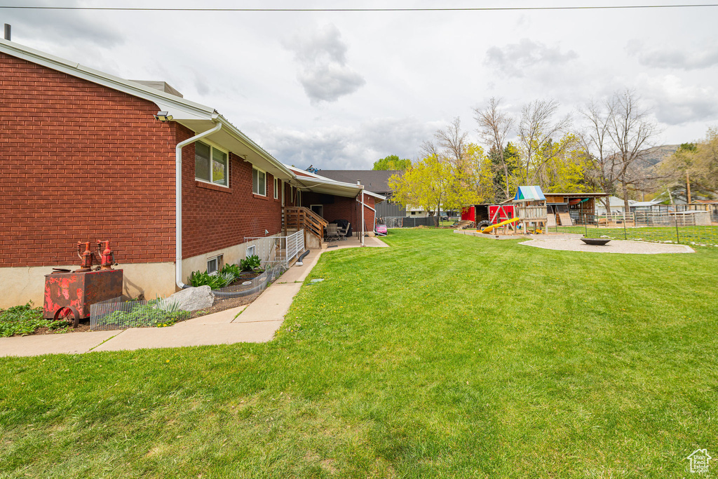 View of yard with a playground, fence, and an outdoor fire pit