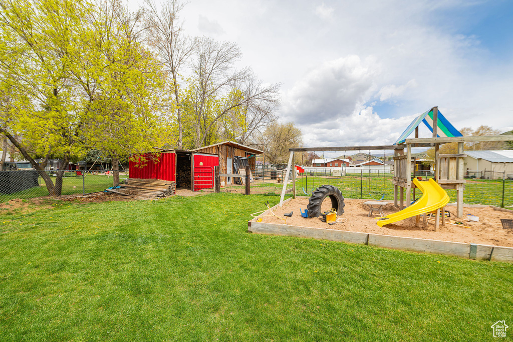 View of playground featuring a lawn and fence