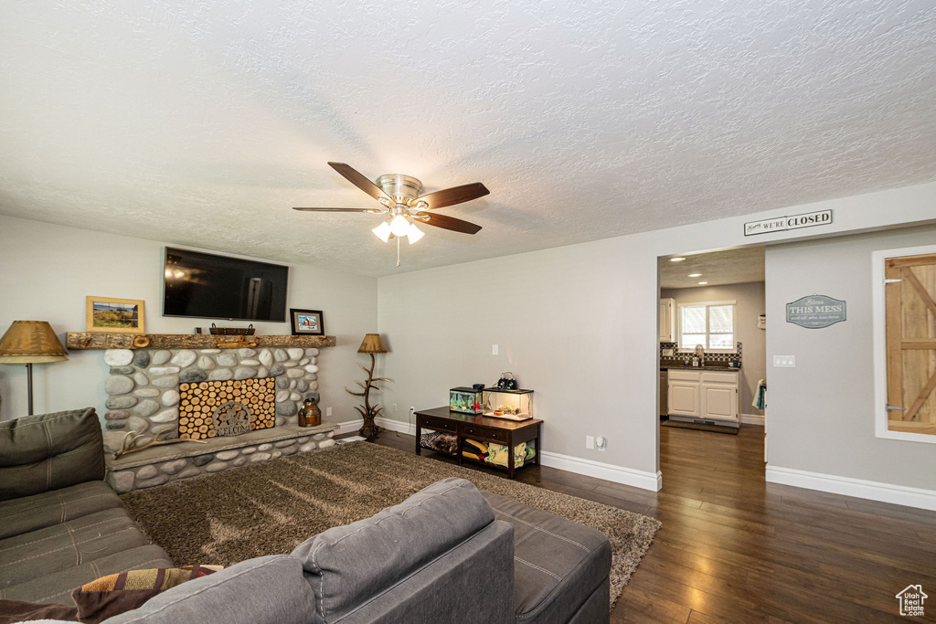 Living area featuring baseboards, ceiling fan, dark wood finished floors, and a textured ceiling