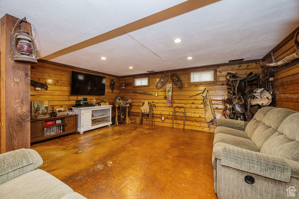 Living room featuring finished concrete floors, wood walls, a textured ceiling, and recessed lighting