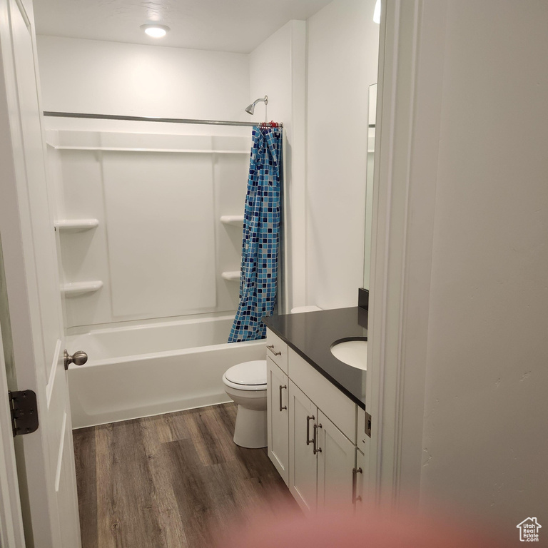 Bathroom with toilet, wood finished floors, shower / bath combo, and vanity