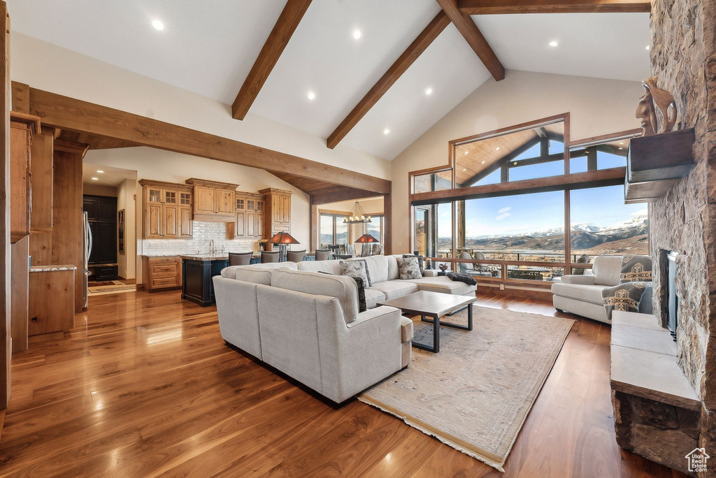 Living room featuring beam ceiling, high vaulted ceiling, wood finished floors, and a wealth of natural light