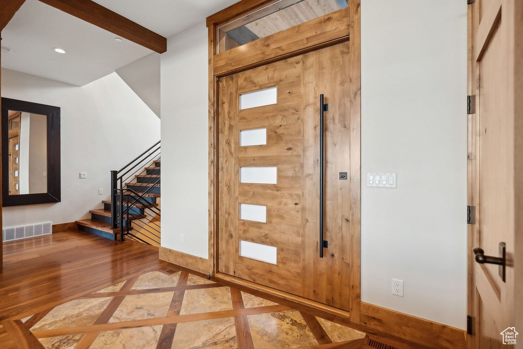 Entryway with wood finished floors, stairs, beamed ceiling, baseboards, and visible vents