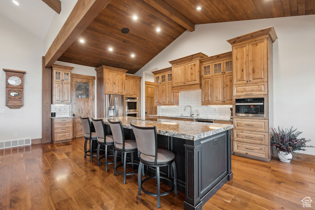 Kitchen featuring recessed lighting, vaulted ceiling with beams, a spacious island, appliances with stainless steel finishes, and a sink