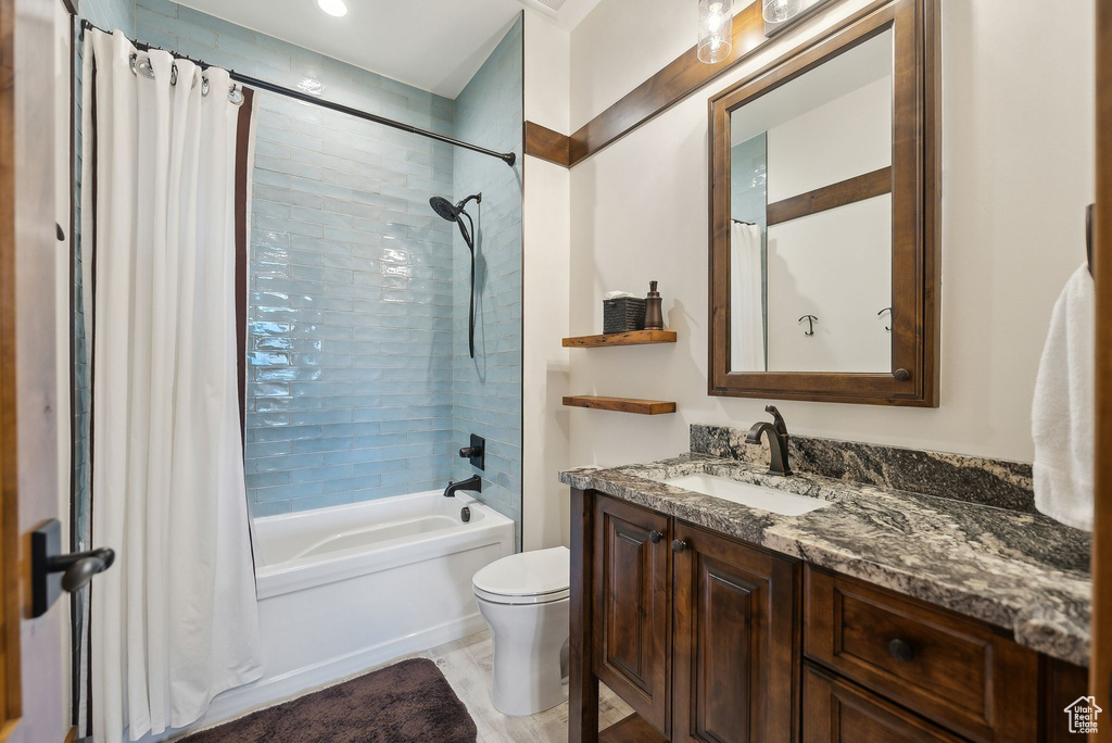 Full bathroom with toilet, shower / bath combo with shower curtain, and vanity