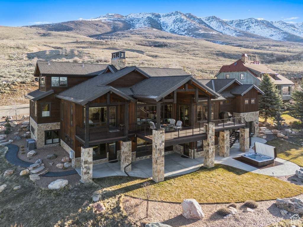 Back of property featuring a patio, a deck with mountain view, stairs, and stone siding