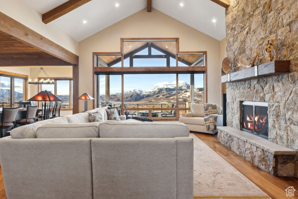 Living area featuring beamed ceiling, high vaulted ceiling, wood finished floors, and a fireplace