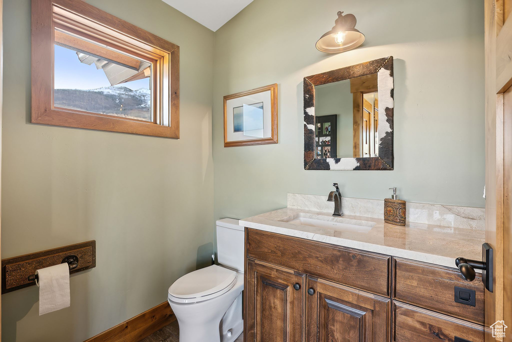 Half bathroom featuring baseboards, toilet, and vanity