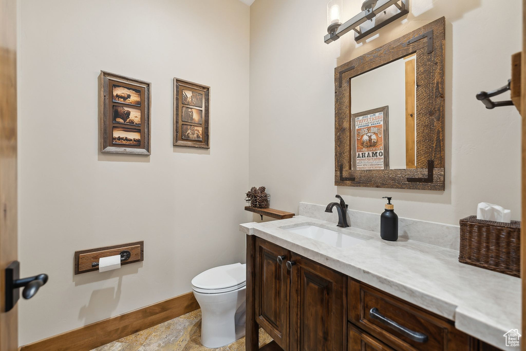Half bathroom featuring toilet, vanity, and baseboards