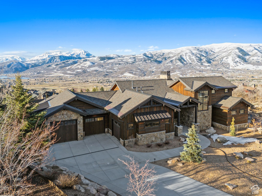 View of front facade with a garage, a mountain view, and stone siding