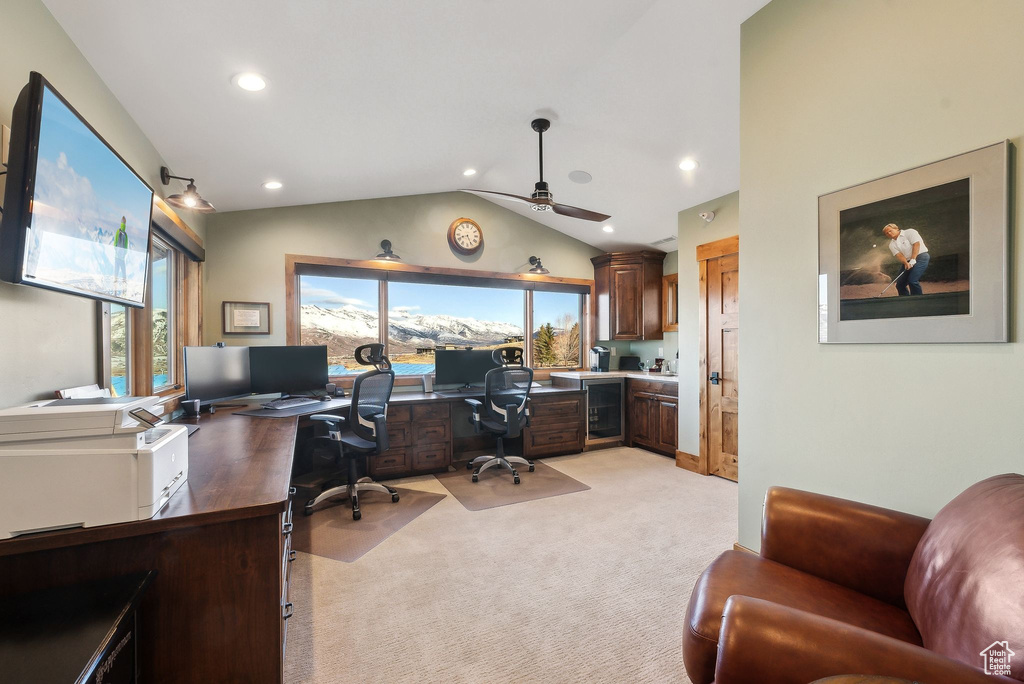 Home office featuring vaulted ceiling, ceiling fan, a wealth of natural light, and light carpet