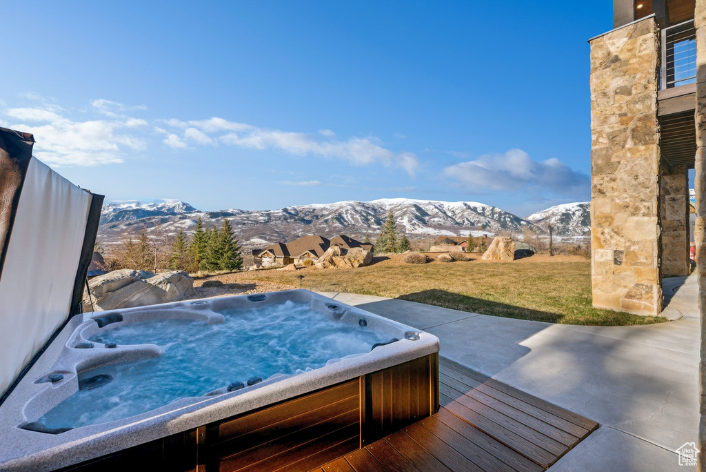 Exterior space with a mountain view, a yard, and a hot tub