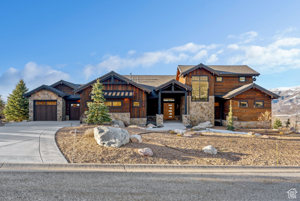 View of front of house with concrete driveway, stone siding, and a garage