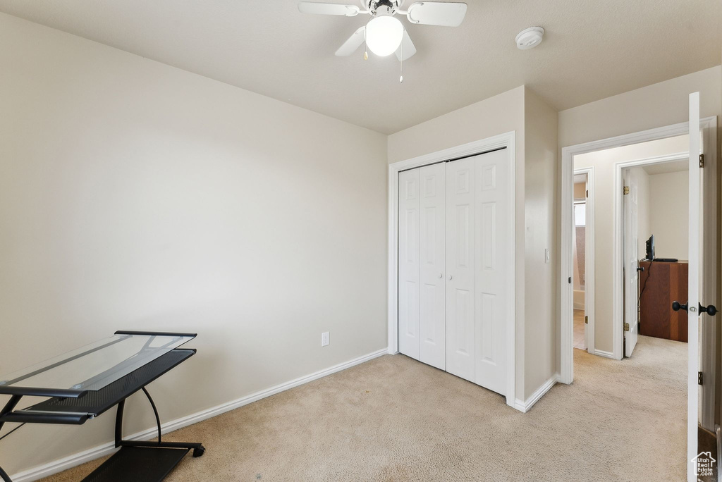 Unfurnished bedroom featuring baseboards, light colored carpet, and a closet