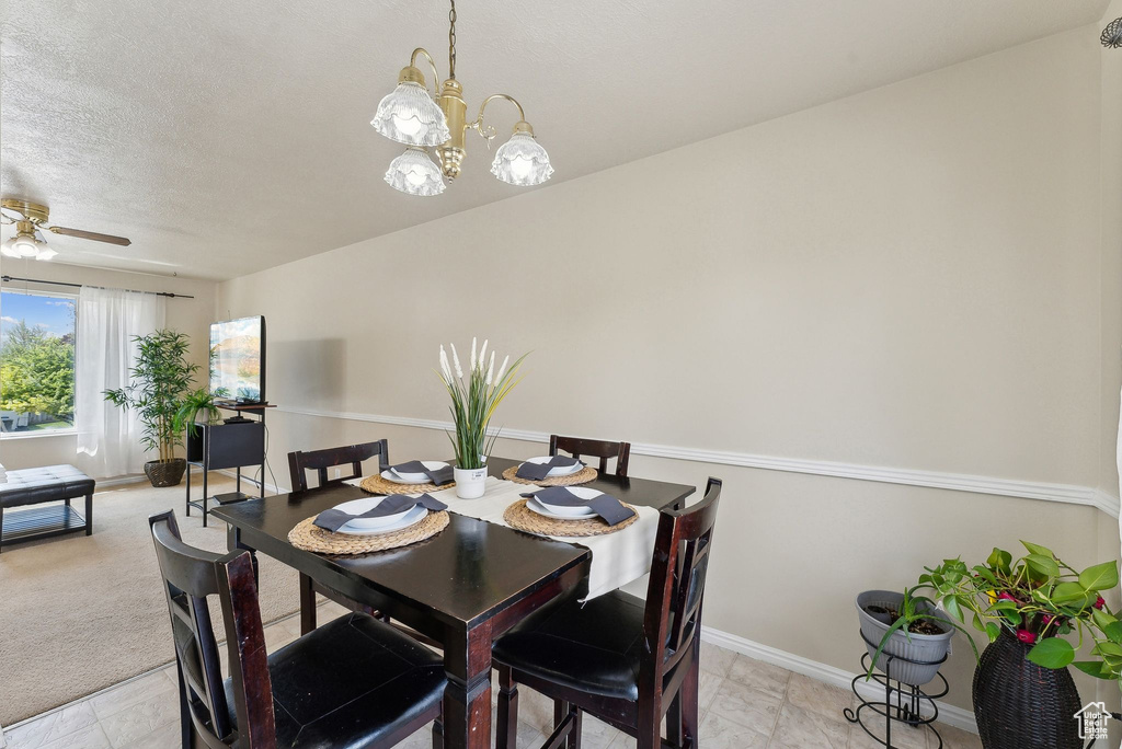 Dining space with baseboards, ceiling fan with notable chandelier, and a textured ceiling