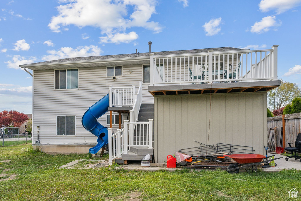 Rear view of house with fence, a yard, and a balcony