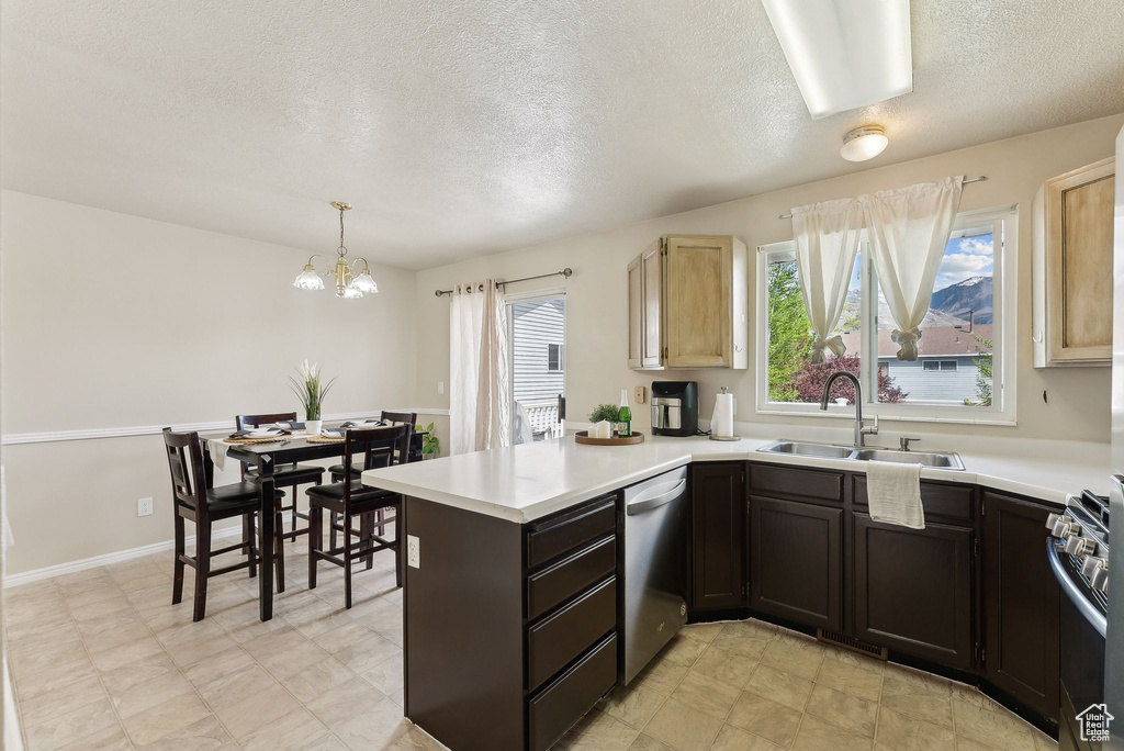 Kitchen with a peninsula, a textured ceiling, a chandelier, a sink, and stainless steel appliances