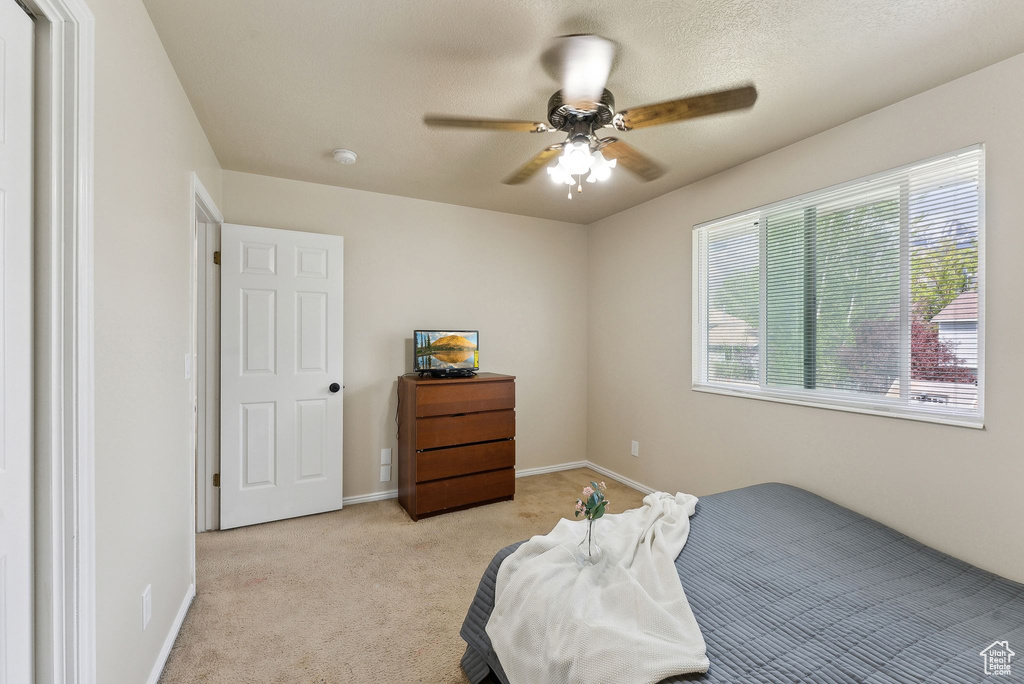 Bedroom featuring baseboards, a ceiling fan, and light carpet