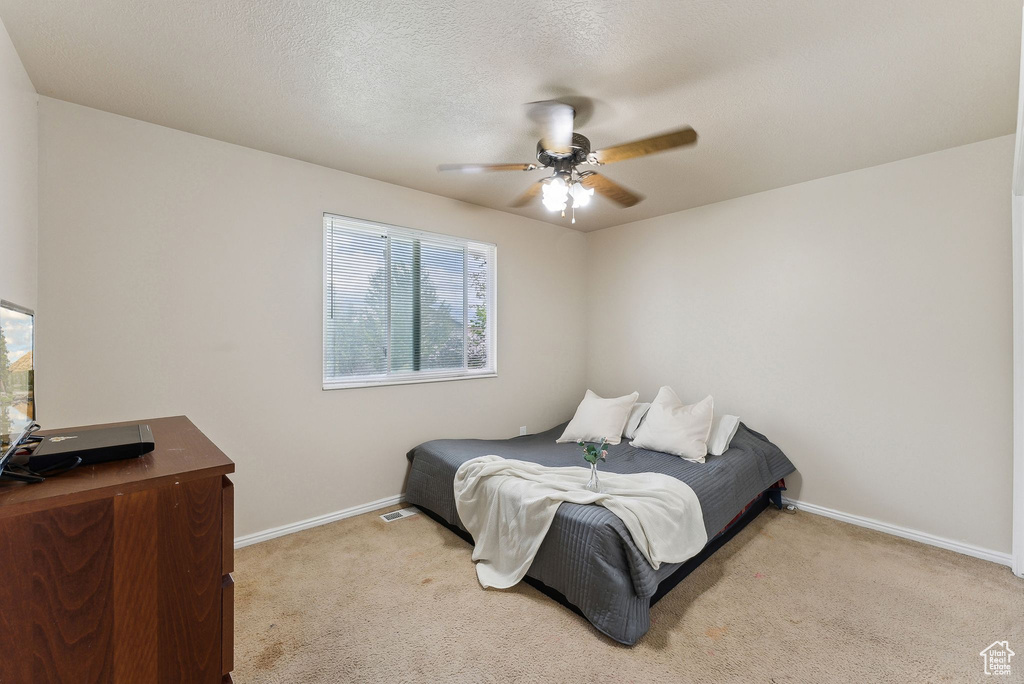 Bedroom with baseboards, ceiling fan, multiple windows, and light colored carpet