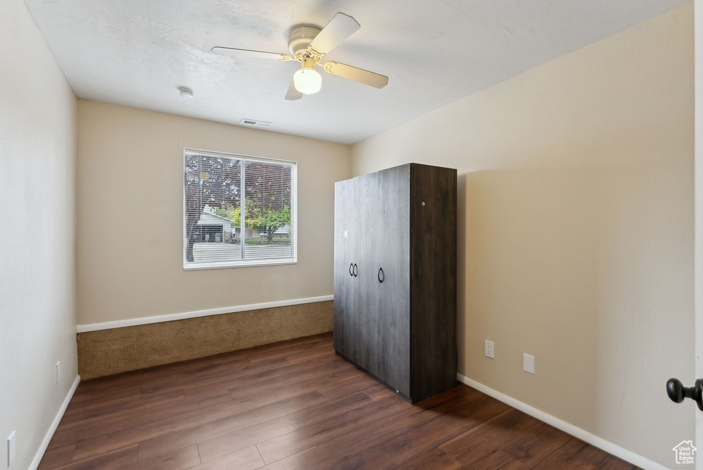 Unfurnished bedroom featuring dark wood-type flooring, a ceiling fan, baseboards, and visible vents