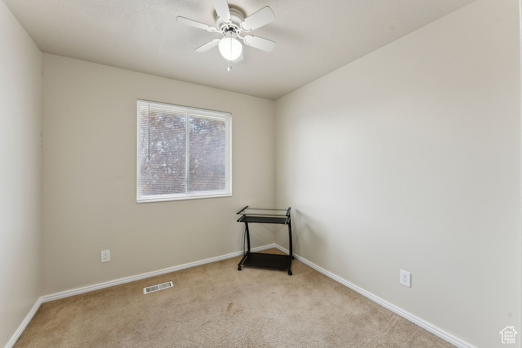 Carpeted empty room featuring visible vents, a ceiling fan, and baseboards