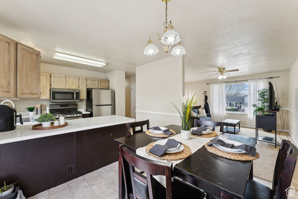 Kitchen featuring light countertops, appliances with stainless steel finishes, light brown cabinetry, and a peninsula