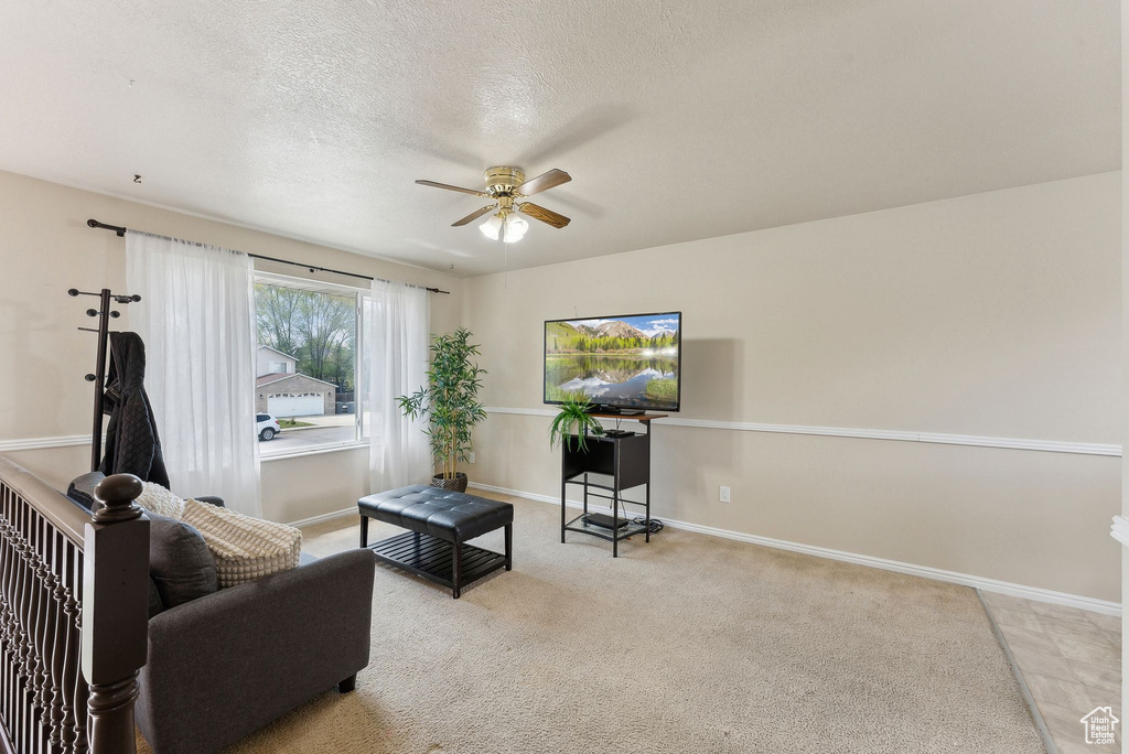 Living area with baseboards, ceiling fan, and a textured ceiling