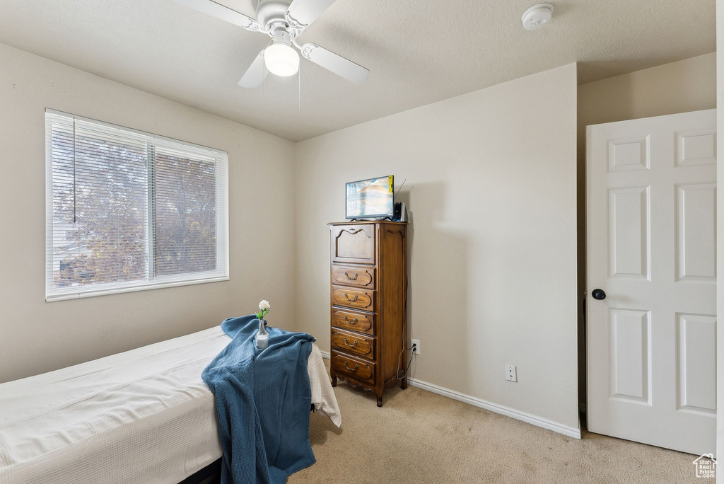 Bedroom featuring light colored carpet, baseboards, and ceiling fan