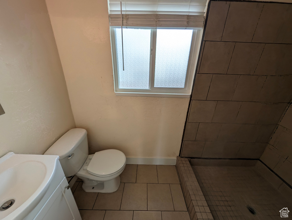 Full bath featuring tile patterned floors, vanity, toilet, and tiled shower