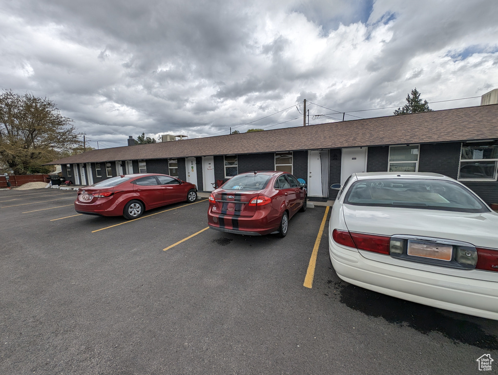 View of front facade featuring uncovered parking and roof with shingles