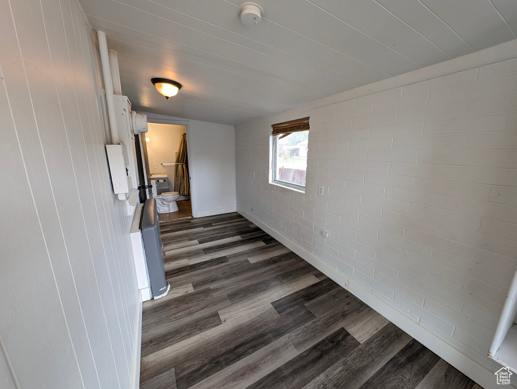 Spare room featuring dark wood-style floors and brick wall